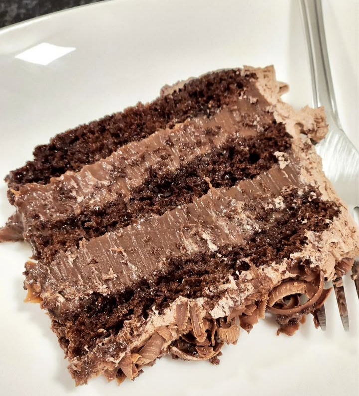 Fatia de bolo de chocolate em camadas com cobertura cremosa